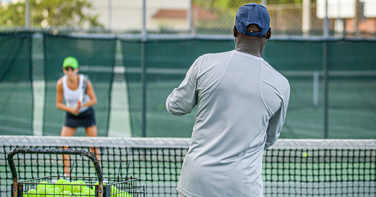 Tennis coach with student on a court.