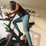 A photograph of a rider using a Peloton studio bike in a home setting