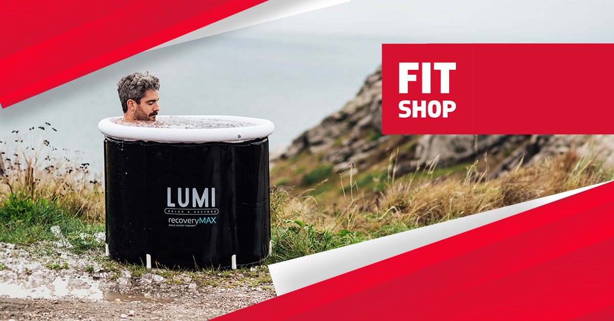 A person relaxing in a LUMI Recovery Pod ice bath, set against a backdrop of rolling hills and a serene outdoor landscape.